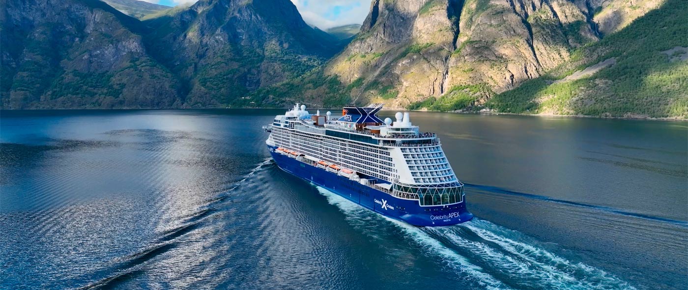 Photo of Celebrity ship sailing by large mountains.