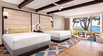 Image features two king beds, exposed ceiling beams, and a sliding glass door opening to an outdoor patio area