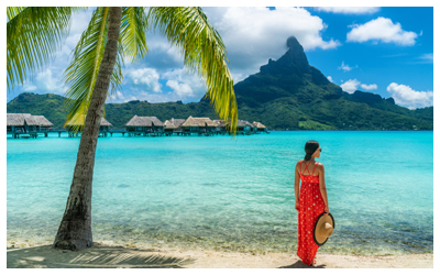 Image of a guest looking across the ocean to mountains and overwater bungalows.