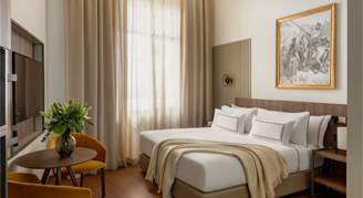 Photo of hotel room with a bed, windows and a small sitting area.