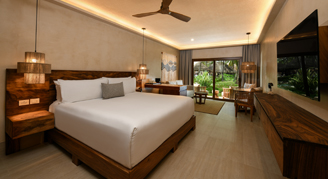 Photo of hotel room with bed, living space and balcony with a garden view.