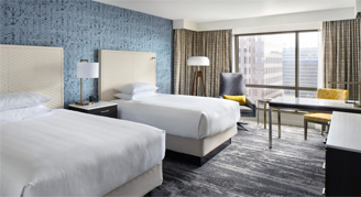 Image of two beds leading to a work area and window in a Standard Room.