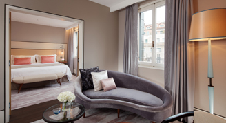 A single bed in a separate room with a chase lounge seating area in the foreground.