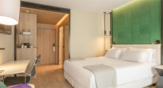 Photo of hotel room with queen bed and desk.