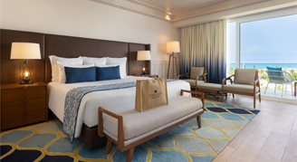 Photo of hotel room with king-sized bed and large balcony windows.
