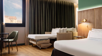 A king bed next to a sleeper sofa and a desk across from them.