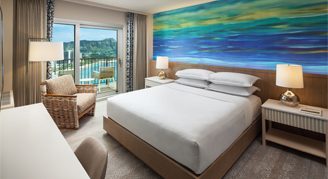 Image of a bed leading to a balcony in a Deluxe Oceanfront Room.