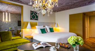 A view of the Deluxe Room with one king bed and a chandelier.