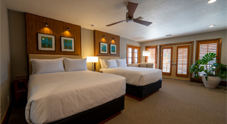 Image shows a king bed with whitle linen and pillows and with slightly opened blinds