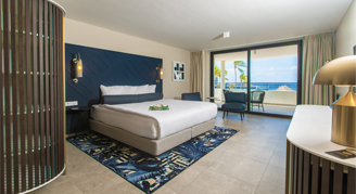 Image of a single bed in a Deluxe Ocean-Vire Room leading to a balcony.