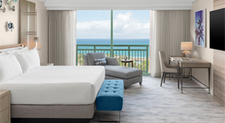 One bedroom grand suite with a king bed mounted tv and a view of the ocean