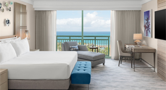 One bedroom grand suite with a king bed mounted tv and a view of the ocean