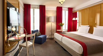 Hotel room with twin beds, lamps and a writing desk.