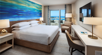 Image of a bed and work area leading to a balcony in an Oceanfront Room.