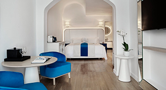Clean white hotel room, open doorway bed area.