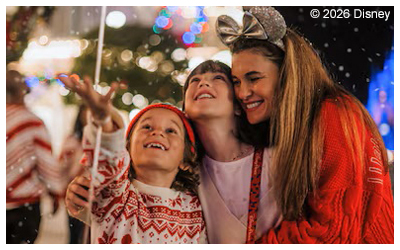 Photo of a woman with two kids smiling at artificial snow falling.