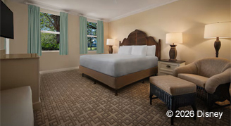 Mobility accessable one-bedroom villa with a King bed with a decorative wooden headboard and sofa chair.