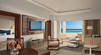 A separate bedroom in the background from a living and dining area and a balcony oceanfront view.