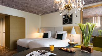 A view of a Deluxe Room with two twin beds and a chandelier.