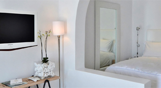 TV mounted in a all white room near white bedroom.