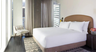 Photo of hotel room with one bed and small seating area.