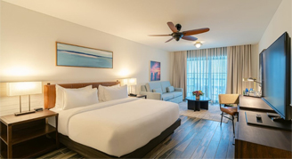 Image of a single bed, television and couch leading to a balcony in a River-View Room.