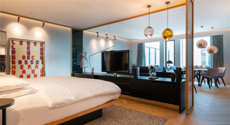 Image of the sleeping area in the Andaz Art Suite open to the seating and dining area.