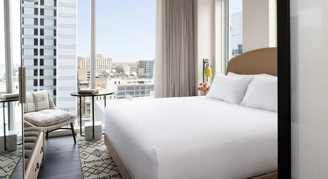 Photo of hotel room with one bed and large windows.