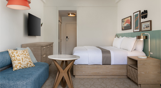 a view of king Bed and a couch with small table and tv mounted on the wall
