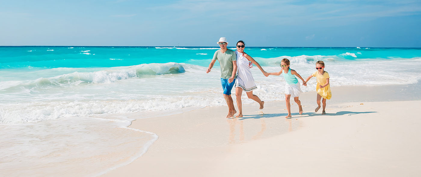Man, woman with two little girls walking on the beach