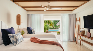 A view of two beds and a T.V. with a view out the sliding doors to the pool.