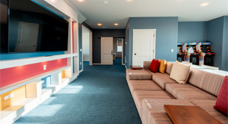 The image shows a living area with mounted tv and couches.