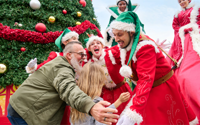 Family with holiday characters next to Christmas tree at Universal Orlando