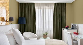 A room with one bed a reading spot and a desk.