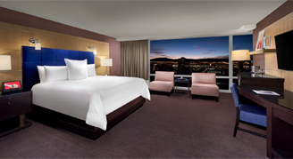 Image shows a king bed with a expansive window view of the city