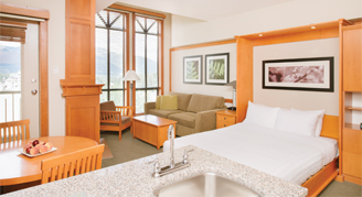 Room with view of the bed, couch, coffee table, and window with view outside.