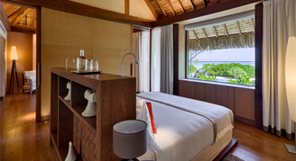 Image of a bedroom with a window open to the beach and ocean.