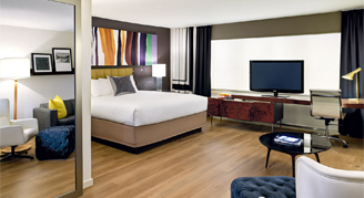 Image of one bed in a room with a monitor in a Junior Apartment.