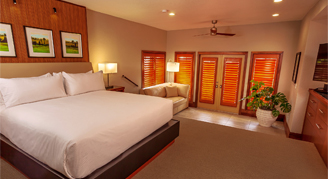 Image shows a king bed with wooden panel base and three portraits above it.