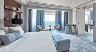 Photo of hotel suite with floor-to-ceiling windows looking at the sea.