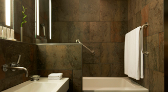 A bathtub in the background and a sink in the foreground of this bathroom.