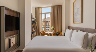 Photo of hotel room with a bed and small sitting area.