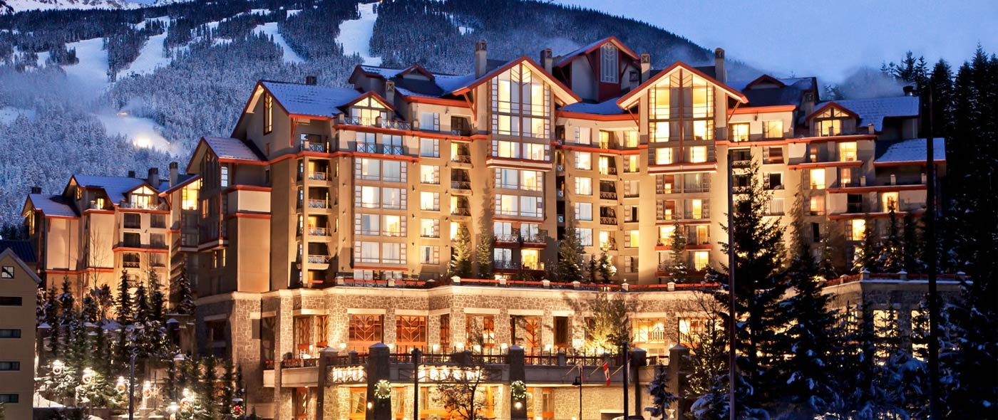 Image of the front of the The Westin Resort & Spa, Whistler with snowy mountains and trees in the background.