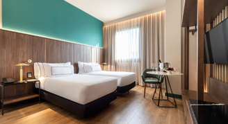 Two beds with a seating area and television.