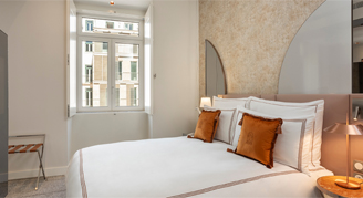 Image shows  a plush king bed with burnt-orange accent pillows.